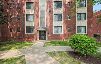 exterior view of a brick apartment building with sidewalks and grass