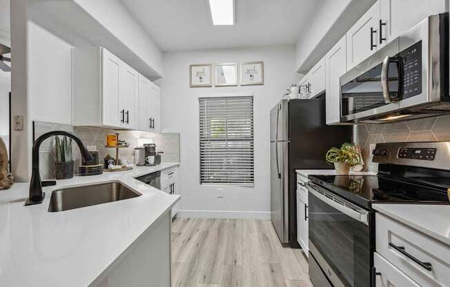 A modern kitchen with black appliances and white cabinets. at Lazo Apartment Homes, Chandler, AZ