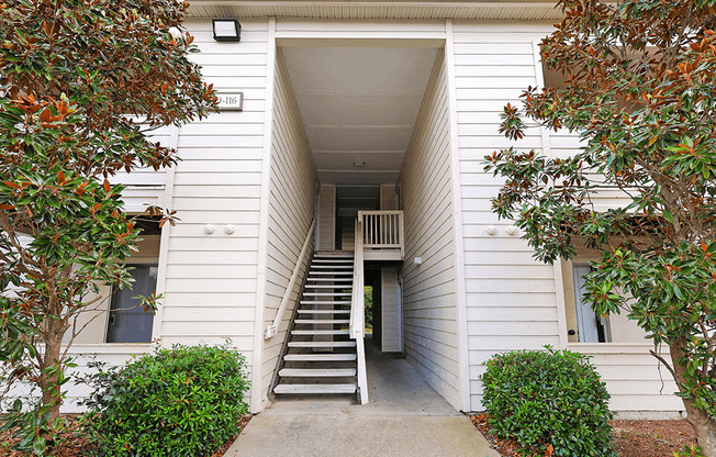 the exterior of a white building with stairs and a sidewalk