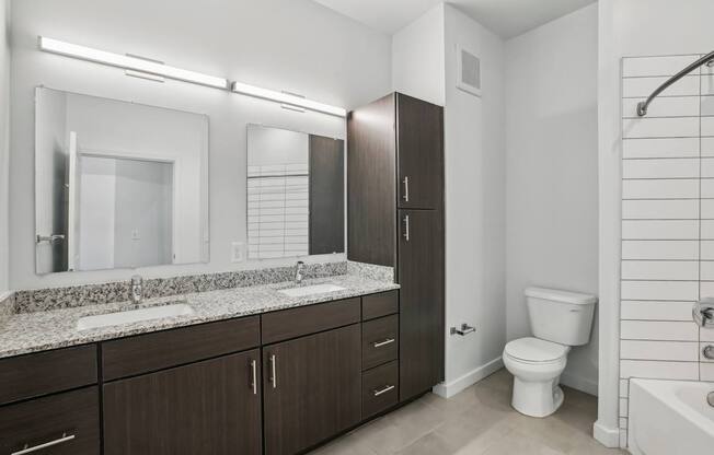 A modern bathroom with a marble countertop and dark wood cabinets.