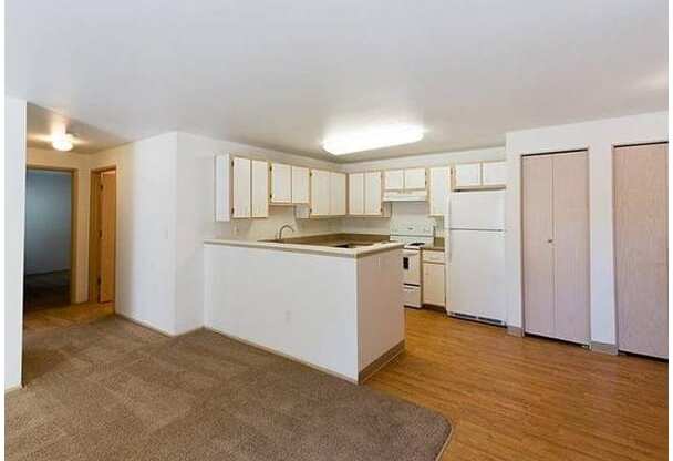 A kitchen with white cabinets and a brown rug on the floor.