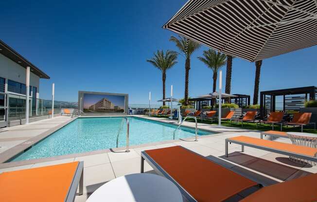 a large swimming pool with lounge chairs and umbrellas on a sunny day