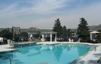 A large swimming pool surrounded by lounge chairs and umbrellas.