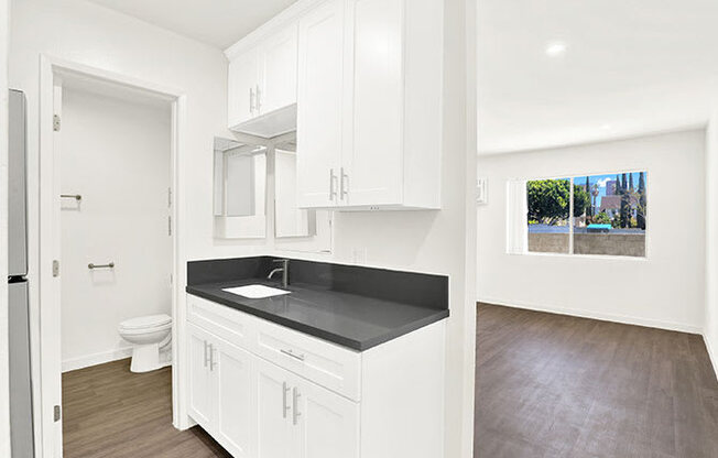 A kitchen with white cabinets and a black countertop.