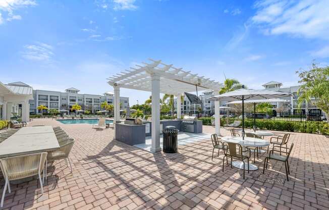 an outdoor patio with tables, grills and chairs and a swimming pool