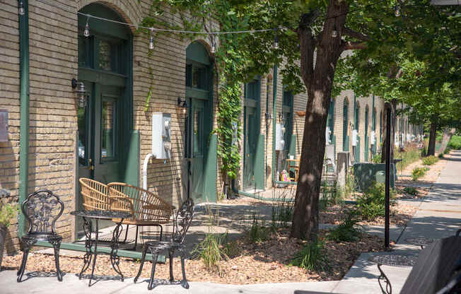 A tree stands next to a bench in front of a building.