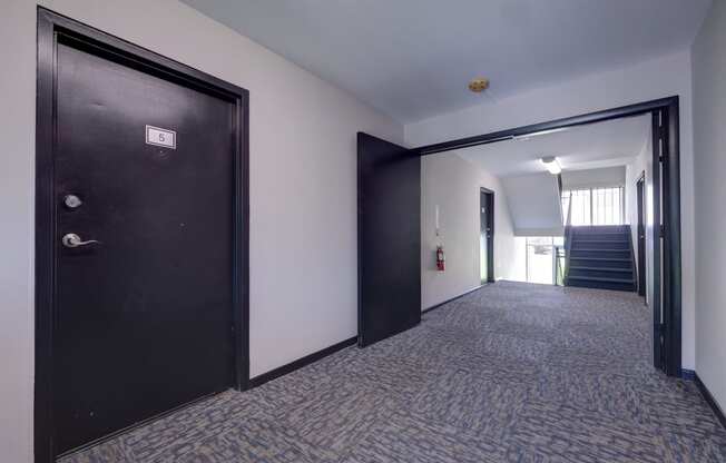 a hallway with a black door and a staircase in a building at Highland Club apartments, Watervliet, NY 12189