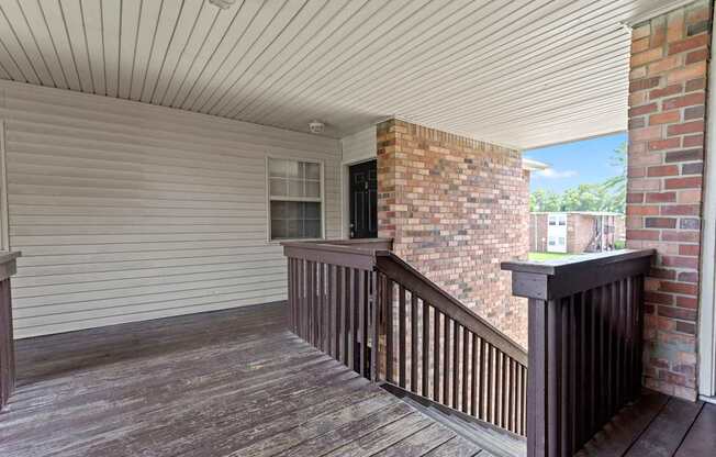 a balcony with a wooden railing and a brick wall