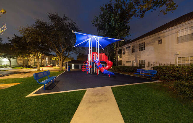 Community Playground with Slide and Blue Canopy at Vinings at Hunter's Green Apartments in Tampa, FL.