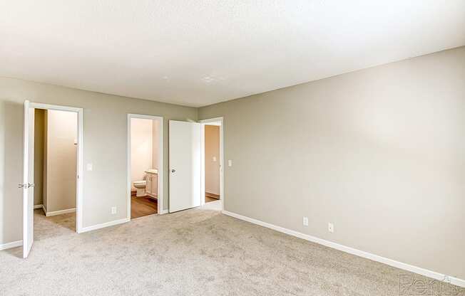an empty room with a carpeted floor and a door to a bedroom