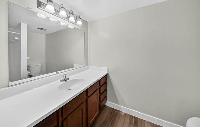 A bathroom with a white countertop and brown drawers.