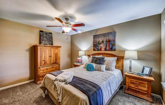 the master bedroom has a king sized bed and a ceiling fan