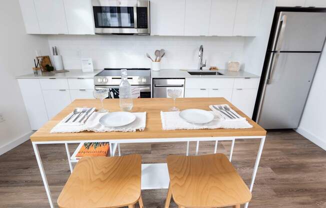 a kitchen with white cabinets and a wooden table with two chairs