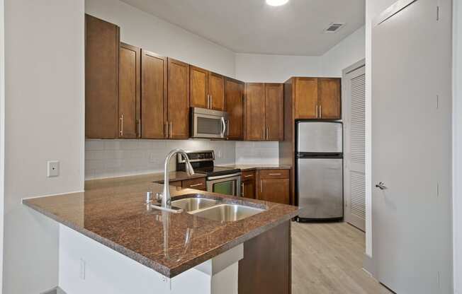 Kitchen with a granite counter top and a sink at The Monterey by Windsor, Dallas, Texas