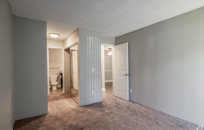 an empty living room with a door open to a bathroom