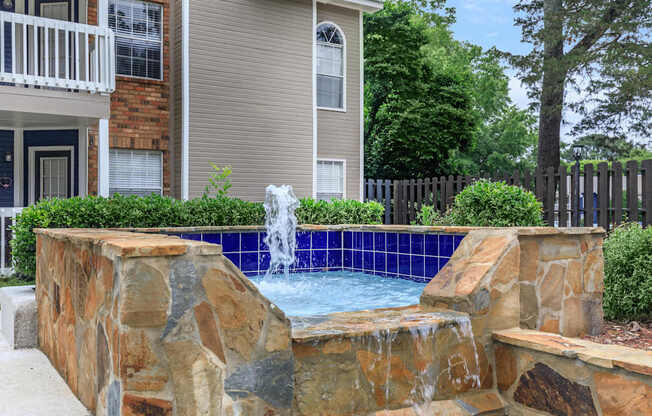 a pool with a fountain in front of a house at The Davis Apartments, Alabama  