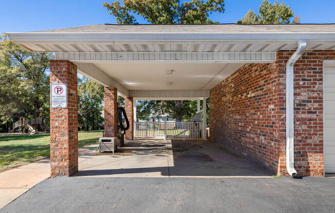 A parking sign is on a brick pillar under a covered parking area.
