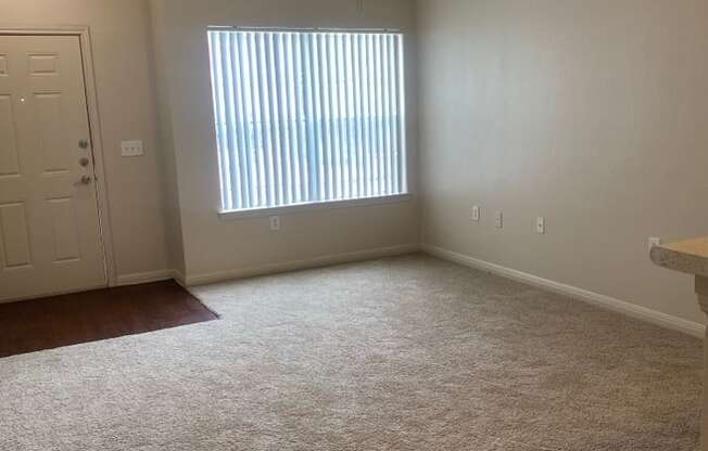 an empty living room with a window and a ceiling fan