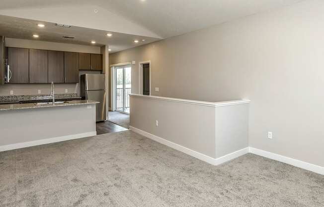 A spacious living room with a kitchen area in the background.