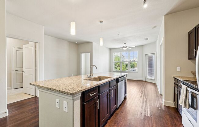 A kitchen with a granite countertop and dark wood cabinets.