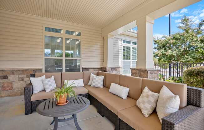 A patio with a couch, pillows and a table.