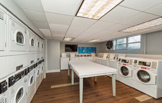 a washer and dryer laundry room with tables and washing machines at The Lafayette Apartments, Colonial Place, Norfolk