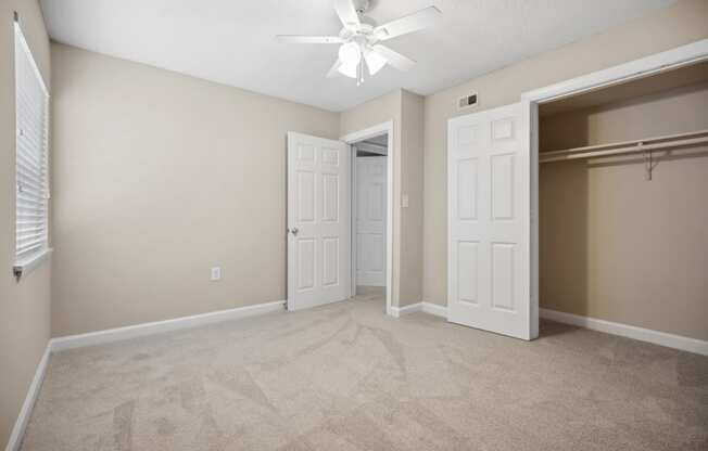 an empty bedroom with a closet and a ceiling fan