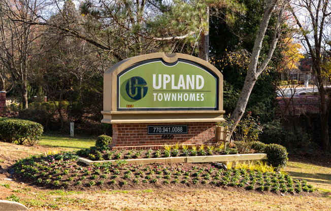 a sign for upland townhomes with trees in the background