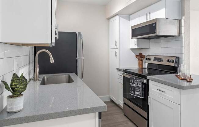 A modern kitchen with a black oven and white cabinets.