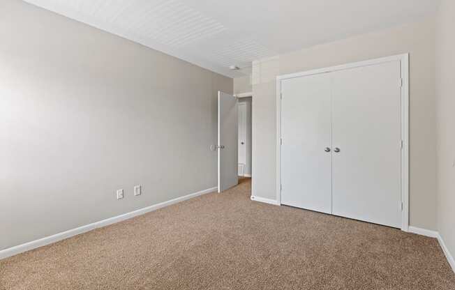 a bedroom with white doors and carpeting and a door to a closet