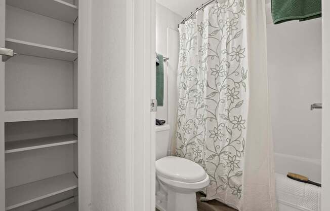 A white toilet in a bathroom with a shower curtain.