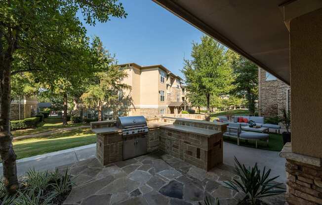 Stone patio with a grill at Woodbridge Villas Apartments, Texas