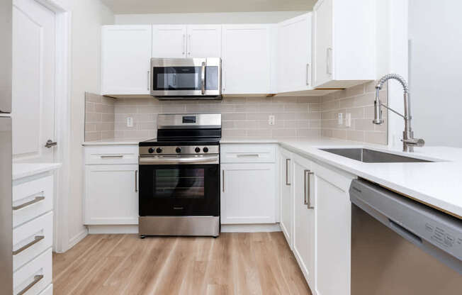 A modern kitchen with white cabinets and a stainless steel oven.