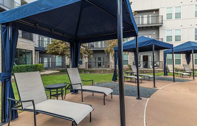 a patio with chairs and umbrellas in front of an apartment building