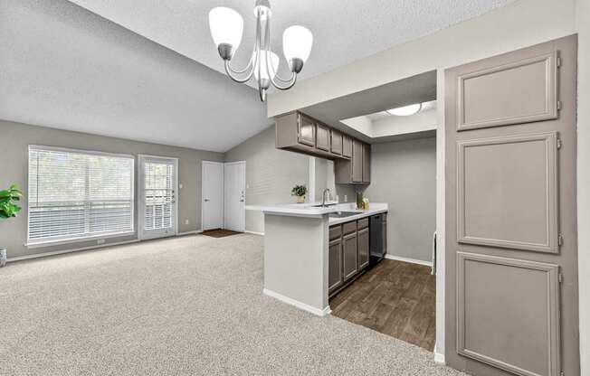 A spacious kitchen and living room with a chandelier and a potted plant.