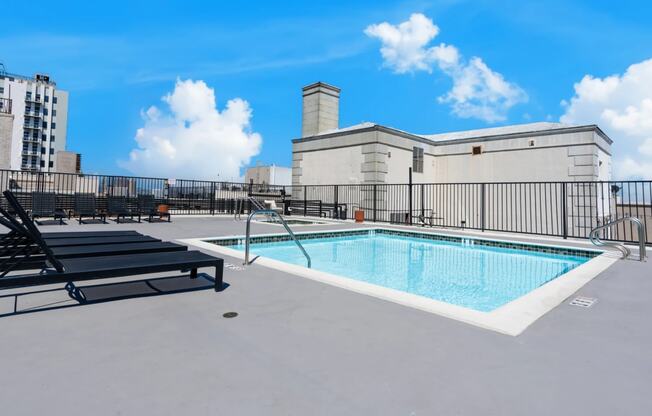 the pool on the rooftop of a building with chairs and a fence