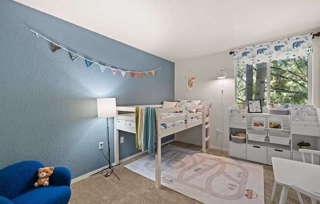 A room with a blue chair and a white and bed frame and desk with a computer at Clackamas Trails Apartments, Oregon, 97222
