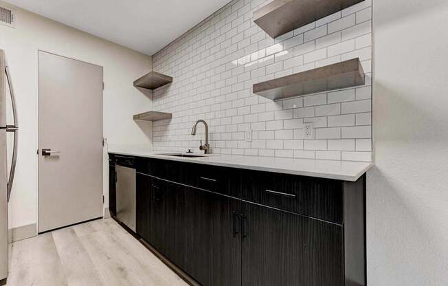 A kitchen with black cabinets and white subway tiles.