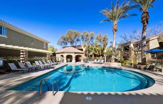 A swimming pool surrounded by sun loungers and palm trees. at The Fairways by Picerne Apartments, Nevada