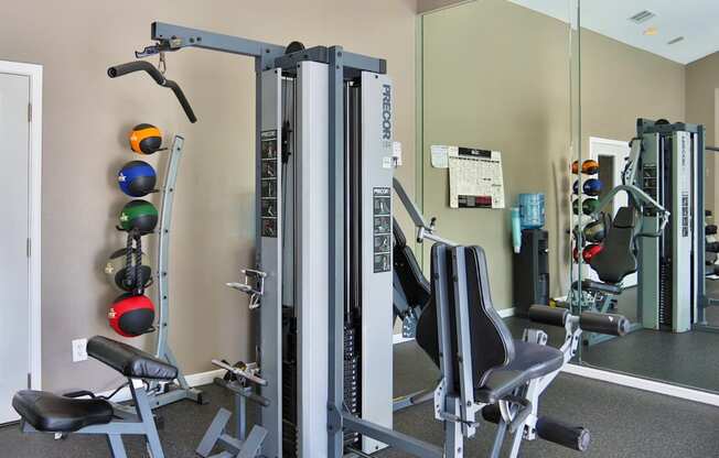 A fitness center with a variety of strength training equipment and weights at The Inverness Apartments in Houston, TX