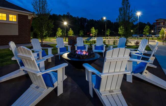 A fire pit surrounded by white chairs.