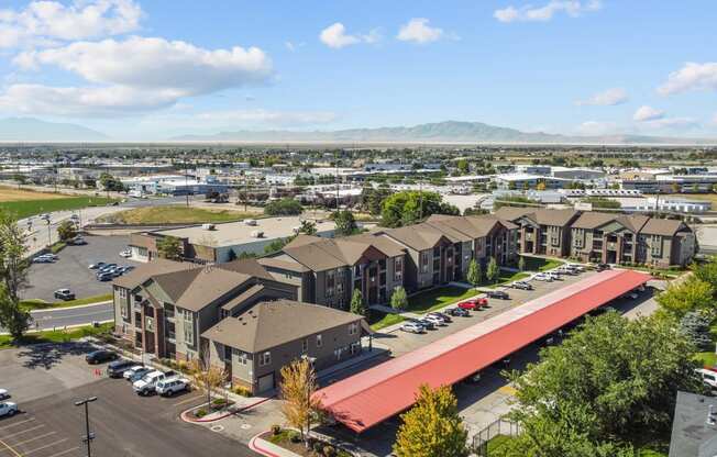 an aerial view of a row of apartment buildings with a parking lot and mountains in the background