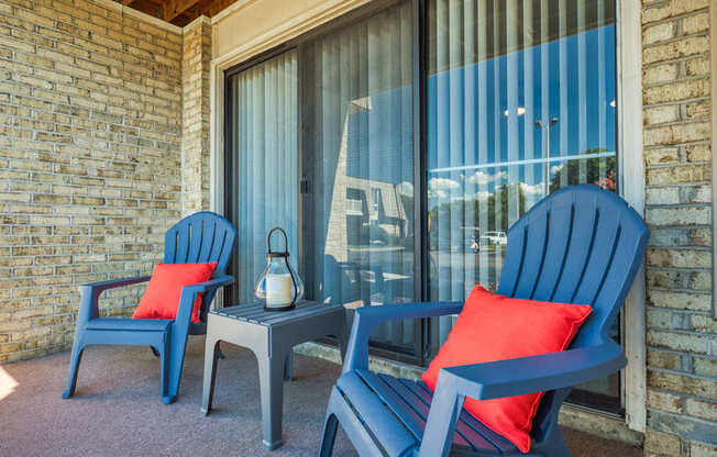 a porch with blue chairs and red pillows