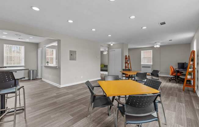 a community room with tables and chairs and a kitchen