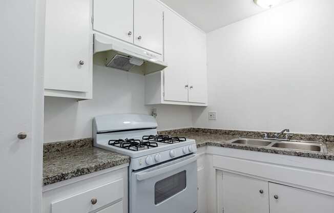 a kitchen with white appliances and granite counter tops and white cabinets