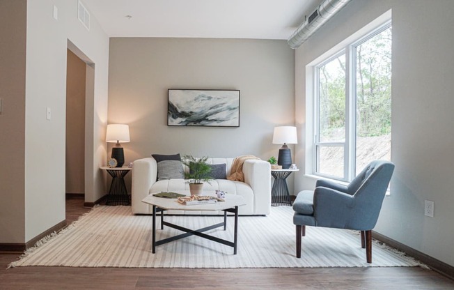 a living room with a couch and a chair and a window