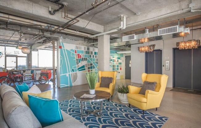 A modern living room with a grey sofa, yellow armchairs, and a patterned rug.