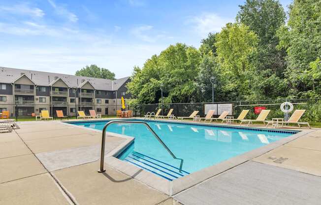 A large swimming pool with a diving board and lounge chairs.