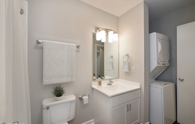 a bathroom with a toilet sink mirror and a washer and dryer