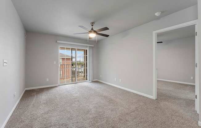 A spacious room with a ceiling fan and a door leading to a balcony.